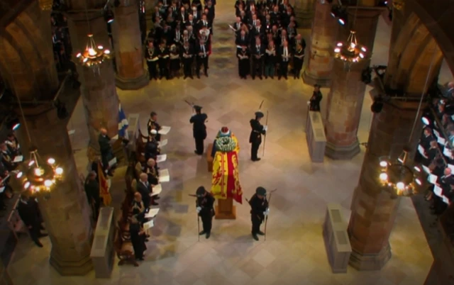 The Queen's coffin is surrounded by four members of the Royal Company of Archers