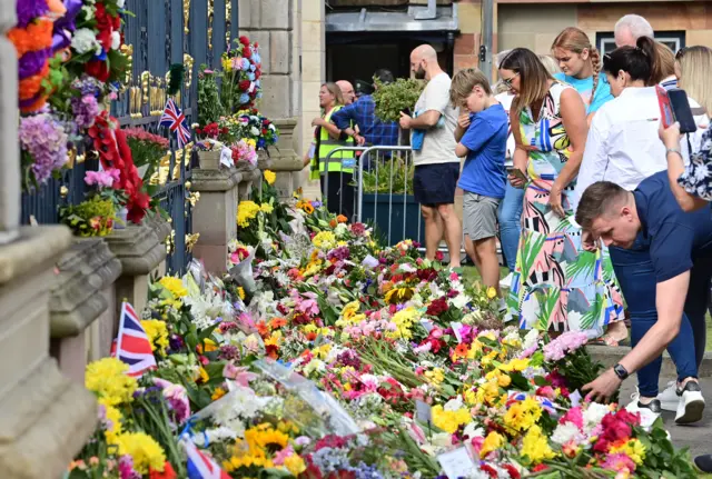 People leaving floral tributes outside of Hillsborough Castle