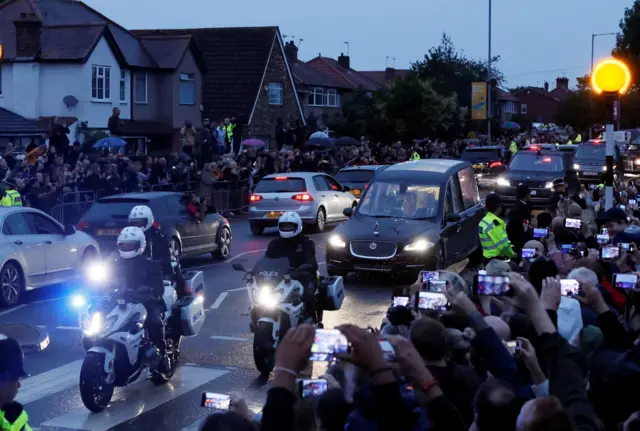 People gather to watch the hearse carrying Queen's coffin as it travels from RAF Northolt to Buckingham Palace