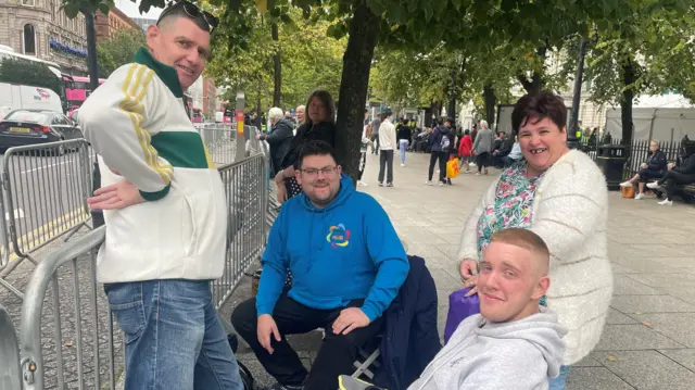 members of the public Simon McGregor, Simon Magee, Travis McGregor and Nicky McGregor sit by the road in Belfast on camp chairs, waiting for the King and Queen Consort