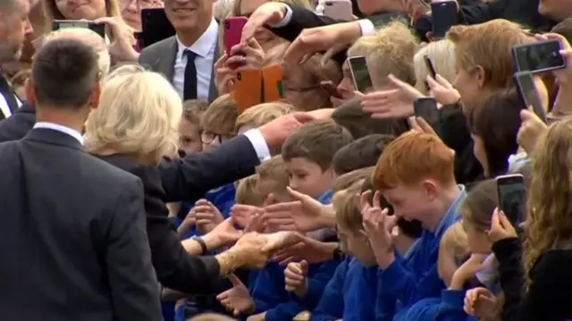 A school child screams after shaking hands with Charles and Camilla