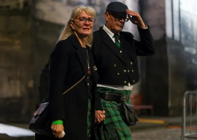 A man in a kilt emerges from the church