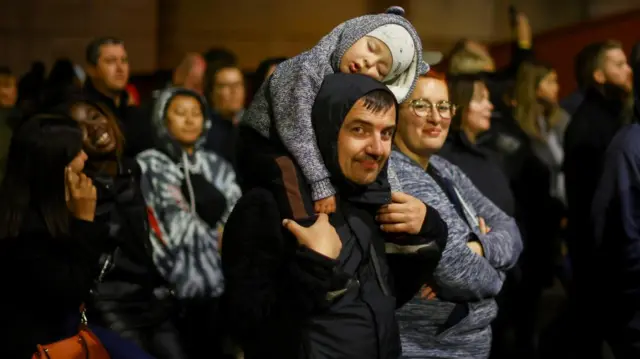 A child asleep on his father's shoulders