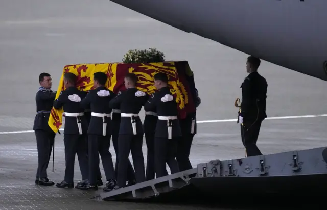 The bearer party from the Queen's Colour Squadron (63 Squadron RAF Regiment) carry the Queen's coffin to the waiting hearse from the plane