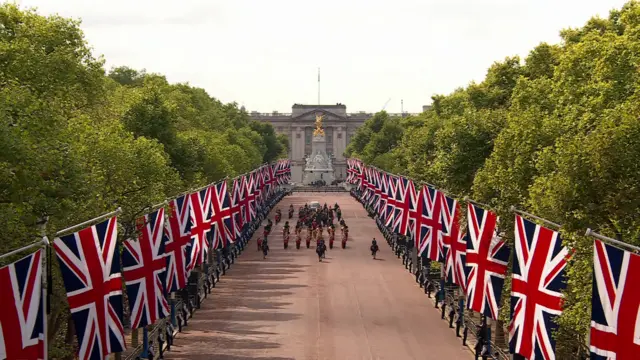 Wide shot of The Mall with the Queen's procession to the Palace of Westminster shown in the centre