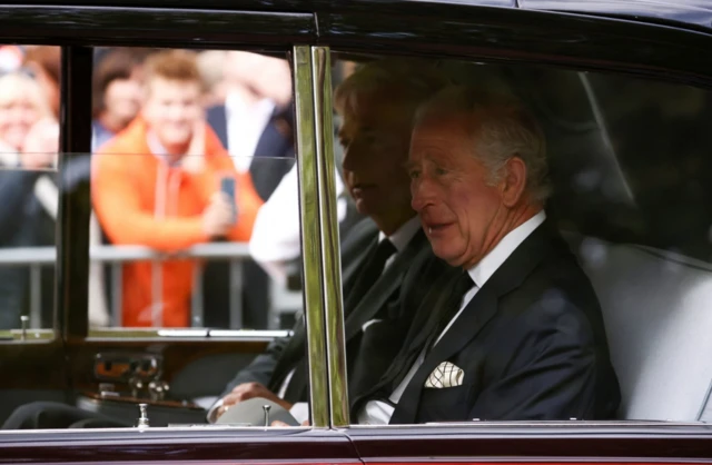 King Charles waves from his car as it drives down the Mall towards Buckingham Palace