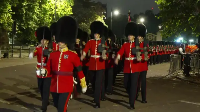 Royal guards march at night before the Queen's coffin is transported to the Palace of Westminster