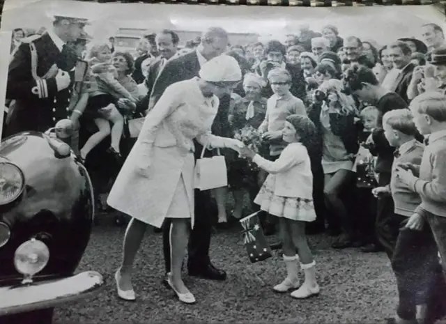 Child handing flowers to the Queen