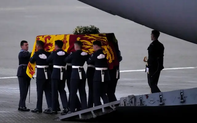 The bearer party from the Queen's Colour Squadron (63 Squadron RAF Regiment) carry the Queen's coffin to the waiting hearse from the plane