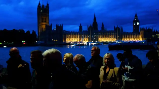 Members of the public stand in the queue on the South Bank in London opposite the Palace of Westminster, as they wait to view Queen Elizabeth II lying in state ahead of her funeral on Monday