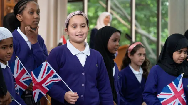 Schoolchildren holding Union Jack flags are pictured at Regent's Park Mosque