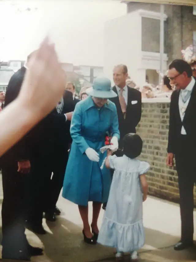 Passing a posy of flowers to the Queen in 1977