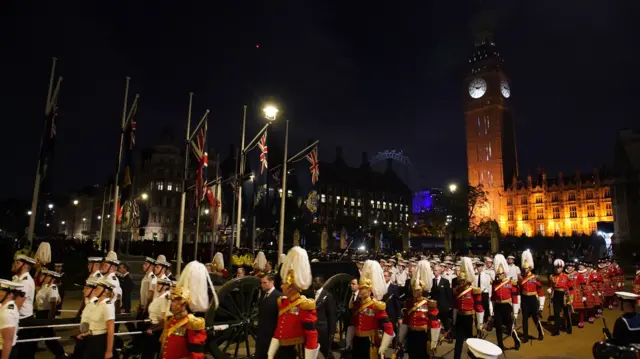 Military officers march outside the Palace of Westminster at 03:00 BST during a rehearsal for the Queen's funeral