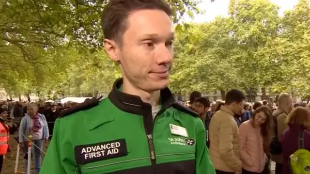 St John Ambulance volunteer Richard Salter standing alongside the queue of people waiting to see the Queen's coffin