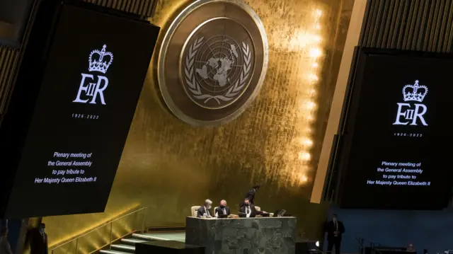 Screens showing with the Queen's ER logo appear during the UN General Assembly's tribute session