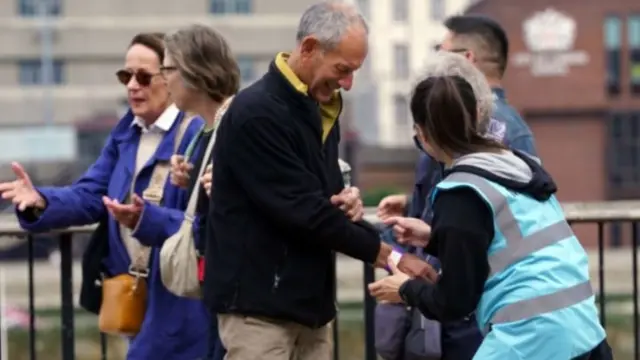 A member of the public gets a wristband as he queues to pay his respects to the Queen