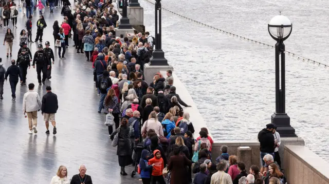 People queue on The Queen's Walk along the River Thames as they wait to pay their respects to the late Queen Elizabeth II lying in state at Westminster Hall