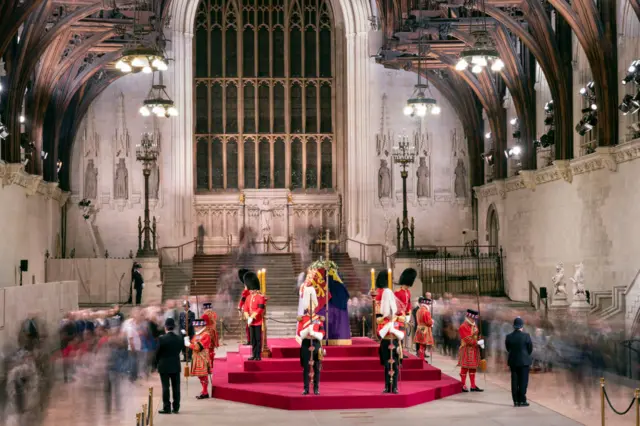 Guards stand around the Queen's coffin inside Westminster Hall as people pay their respects.