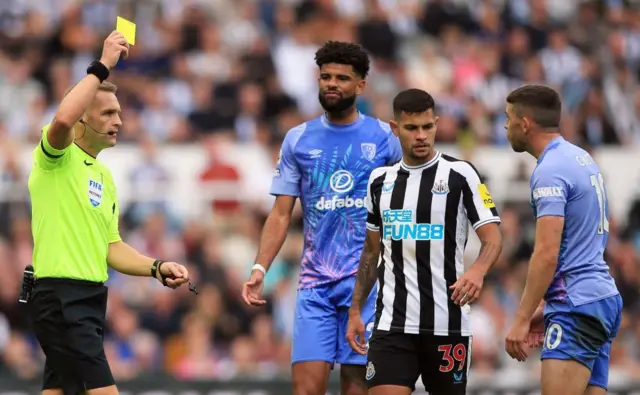 Ryan Christie (R) receives a yellow card