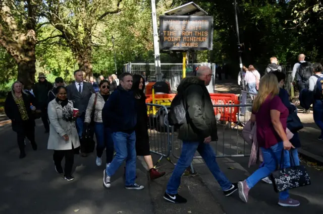 A sign warns people of a minimum 14-hour wait