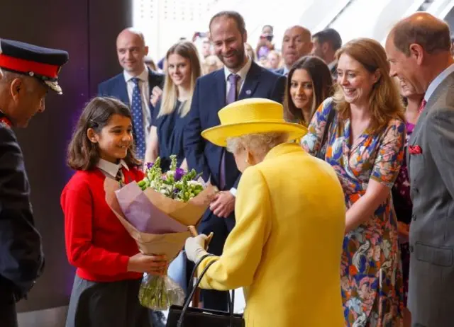 A schoolgirl presents flowers to the Queen