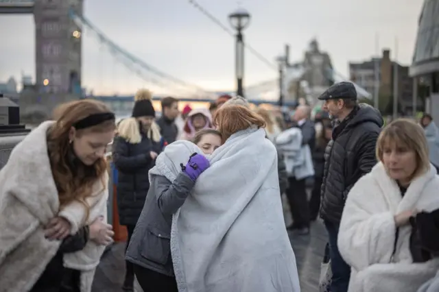 People try to keep warm in the queue near Tower Bridge