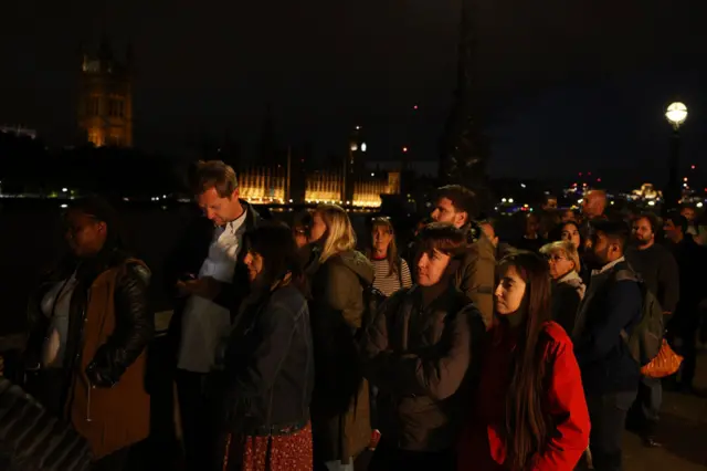 People take part in a one-minute silence which is being held across the UK in Queen Elizabeth II's honour as they stand in a queue along the River Thames waiting to see Queen Elizabeth II lying in state in Westminster Hall on September 18, 2022 in London, England.