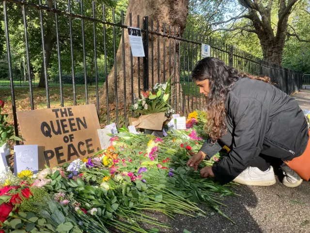 Dee places flowers in Southwark Park