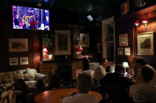 People gather to watch a broadcast of the funeral of Britain's Queen Elizabeth at an English pub in Sydney, Australia