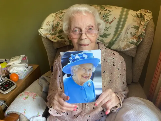 Phyllis Hales holding her card from the Queen