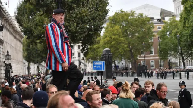 People wait to watch the State Funeral Procession of Queen Elizabeth II