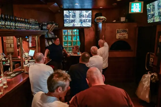 Patrons watch the funeral ceremony for Britain's Queen Elizabeth II at Westminster Abbey in London as it is shown live on television at a British pub in Tokyo