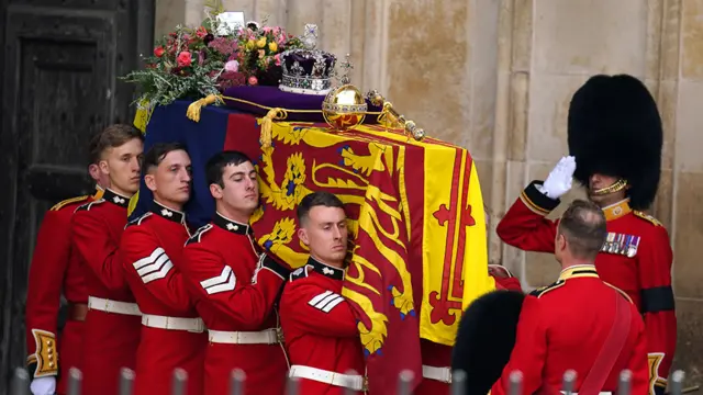 The coffin of Queen Elizabeth II, draped in the Royal Standard with the Imperial State Crown and the Sovereign's orb and sceptre, leaves Westminster Abbey