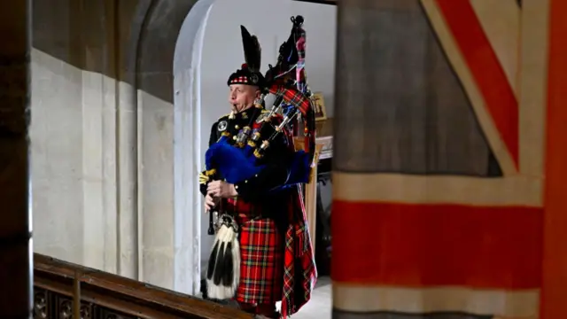 Pipe Major Paul Burns of the Royal Regiment of Scotland helps to close the funeral