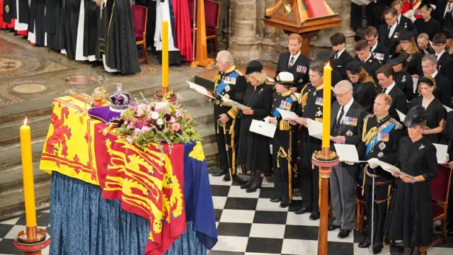 The Queen's family rise to sing a hymn behind her coffin