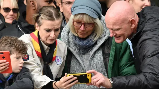 People watch the funeral on their phone