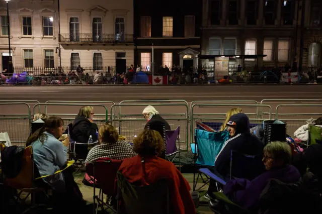 People sit in camping chairs overnight by the funeral procession route for Queen Elizabeth II in London