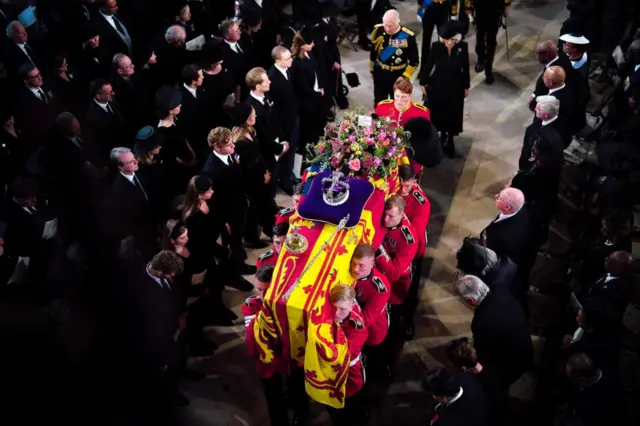 King Charles III and the Queen Consort follow behind the coffin