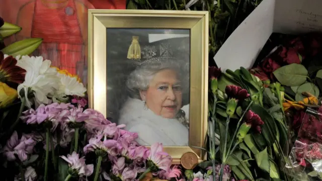 Floral tributes of the Queen are left beside a framed photo of the late monarch