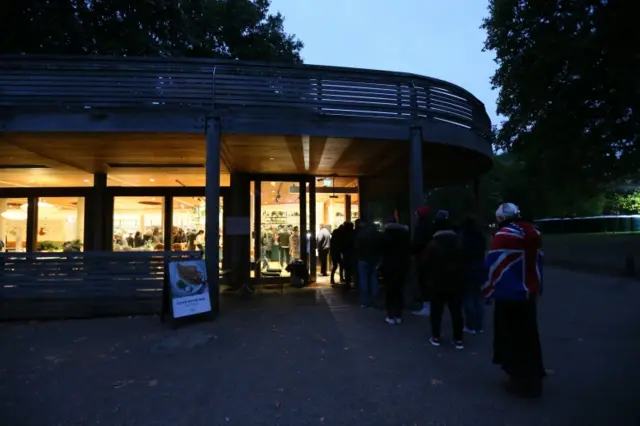 People queue to buy hot drinks before they find a position to watch the State Funeral Procession of Queen Elizabeth II in London on 19 September 2022