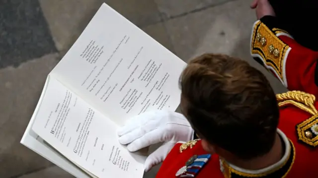 A guest reads the order of service during the Queen's funeral