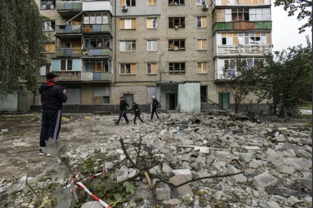 People walk among debris after night shelling in Kharkiv