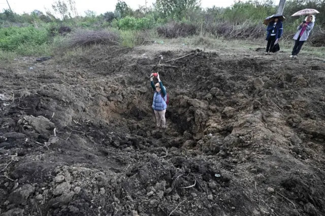 A man stands in the crater left by the bombing near the Pivdennoukrainsk nuclear plant