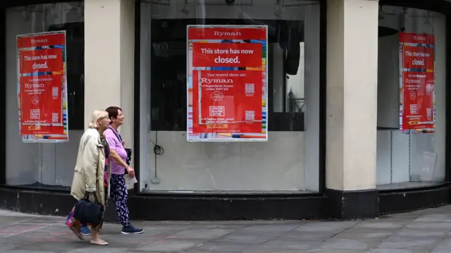 People walk past a closed shop