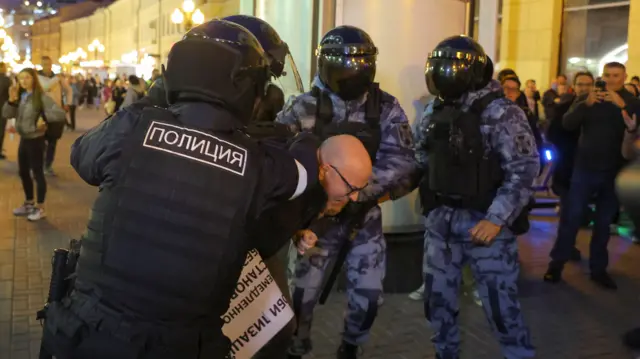 One man was seen being detained by four Russian police officers, all dressed in riot gear, including helmets with dark visors covering their faces