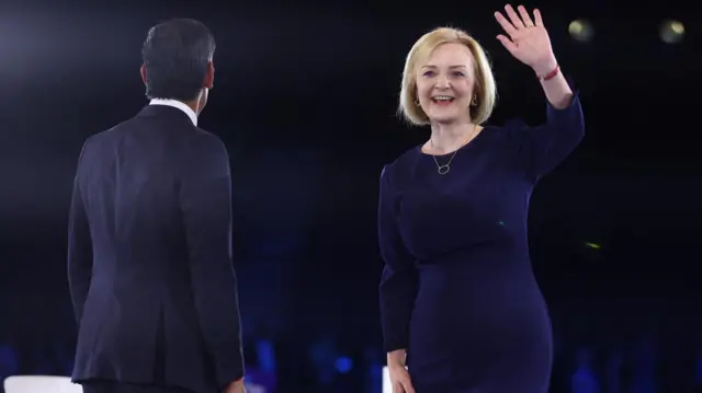 Conservative leadership candidate Liz Truss waves as she stands next to Conservative leadership candidate Rishi Sunak as they attend a hustings event in London.