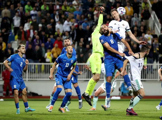 Northern Ireland defender Jonny Evans rises highest to bedat the Kosovo keeper to the ball