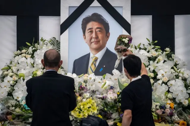 People leave flowers and pay their respects to former Japanese prime minister Shinzo Abe outside the Nippon Budokan in Tokyo on September 27, 2022.