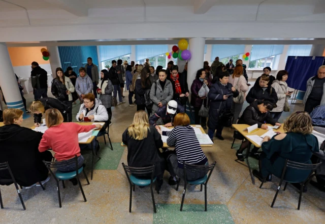 People receive their ballots at a polling station during a referendum on the joining of the self-proclaimed Donetsk People's Republic (DPR) to Russia, in Donetsk, Ukraine September 27, 2022.