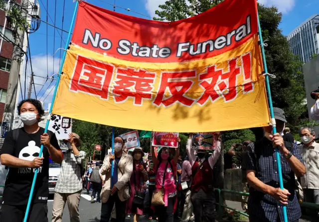 A protestor holds a placard against the state funeral of former Japanese prime minister Shinzo Abe outside the Nippon Budokan in Tokyo on September 27, 2022.